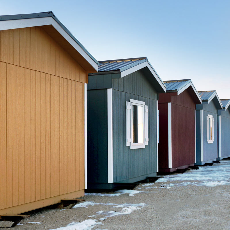 Colorful tiny houses lined up on a snowy lot.